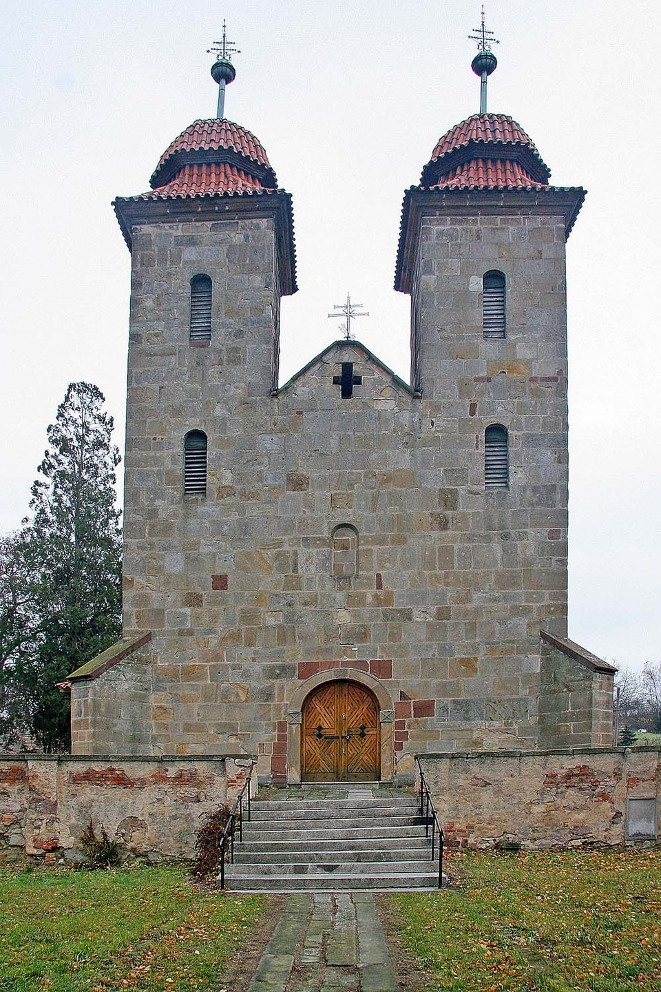 Photo “Tismice – façade of the Romanesque Basilica” by Prazak, licensed under CC BY-SA 3.0 via Wikimedia Commons